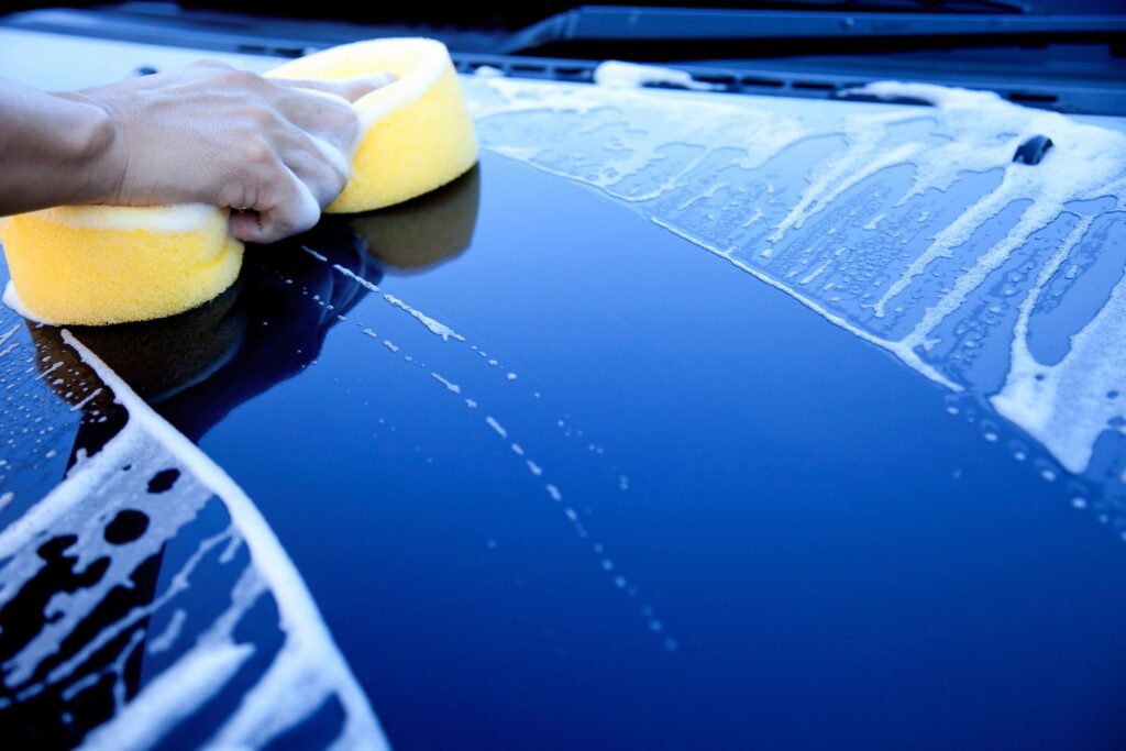 A person cleaning the car using a sponge