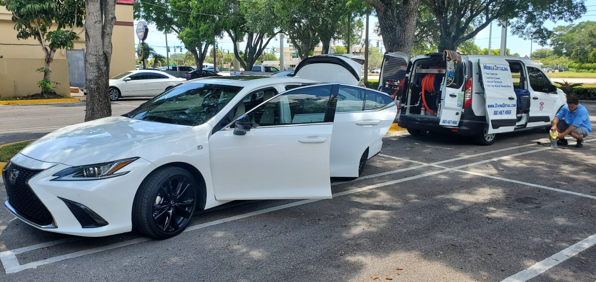 A white car parked in the parking lot with its doors open.