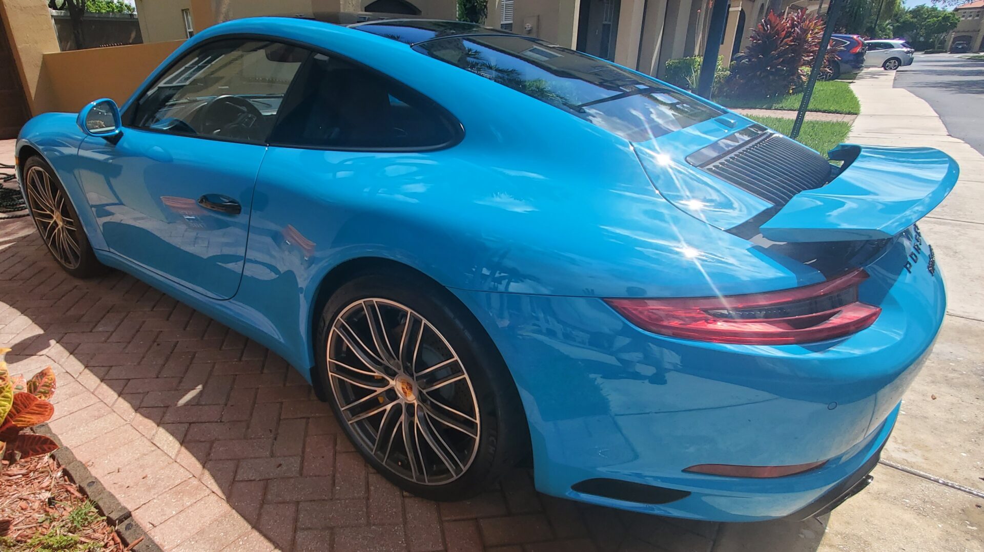 A blue car parked on the side of a road.